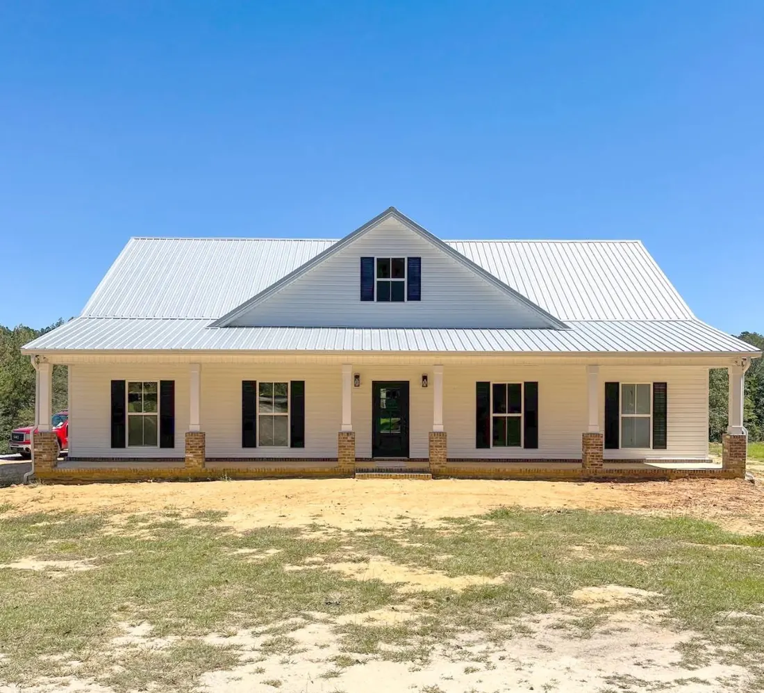 White farmhouse with a metal roof and a long front porch