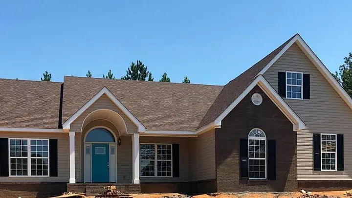 The Audubon plan: brick and siding home with an arched entry and a blue front door