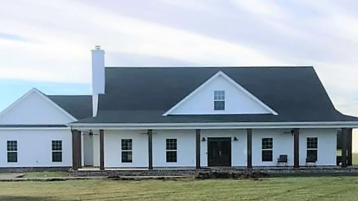 The Cottonwood II plan: white farmhouse with a chimney and a wraparound porch